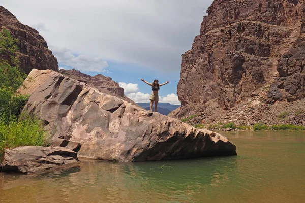 Jonge vrouwelijke backpacker op een groot rotsblok in een rustig stuk van de Colorado rivier in de Grand Canyon. — Stockfoto