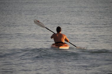 Genç adam gün batımında Captiva Adası 'nda Kano.