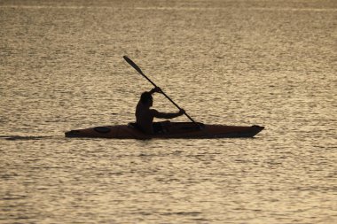 Genç adam gün batımında Captiva Adası 'nda Kano.