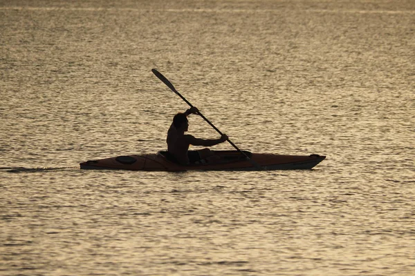 Genç adam gün batımında Captiva Adası 'nda Kano.