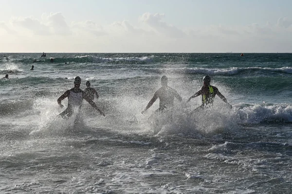 Erkek triatletler 2019 South Beach Triatlon başında sörf girin.