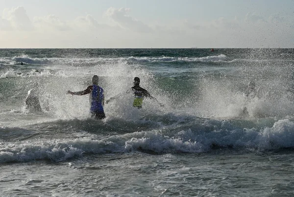 Erkek triatletler 2019 South Beach Triatlon başında sörf girin.