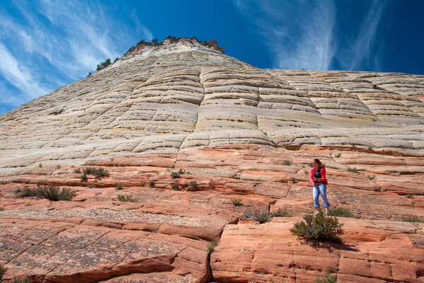 Молодая женщина взбирается на шахматную доску "Меса" на плато Сион, Юта
.