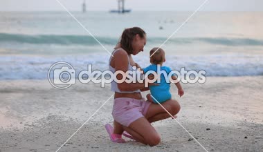 Jimbaran, Bali/Endonezya-01 02 2019: Bali adasında Jimbaran Plajı. Anne ve bebek günbatımı hayran