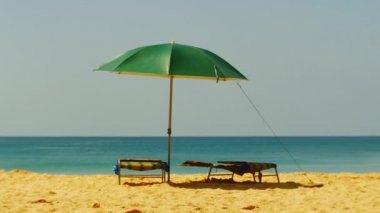 Okyanusun üzerinde sıcak gün, yeşil bir şemsiye ve şezlong çerçevesinde