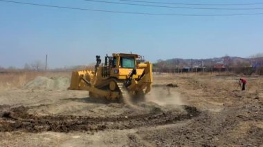 Artem, Primorsky Krai / Rusya - 04 04 2019: Quadrocopter ile Çerçeve. Büyük sarı buldozer toprak bir yolda sürüş