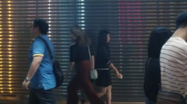 Hong Kong / Hong Kong - 05 22 2019: Hong Kong sakinleri kapalı dükkanın pırıl pırıl kapısının arka planında yürüyorlar