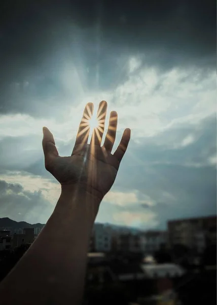 hand of woman praying with hands against sunset sky