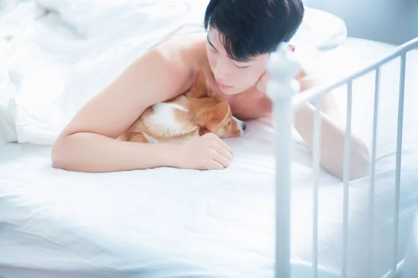 asian man lying with dog in bed