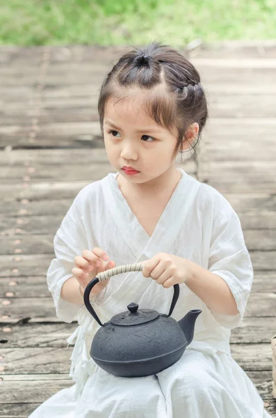 Cute little asian girl with tea kettle