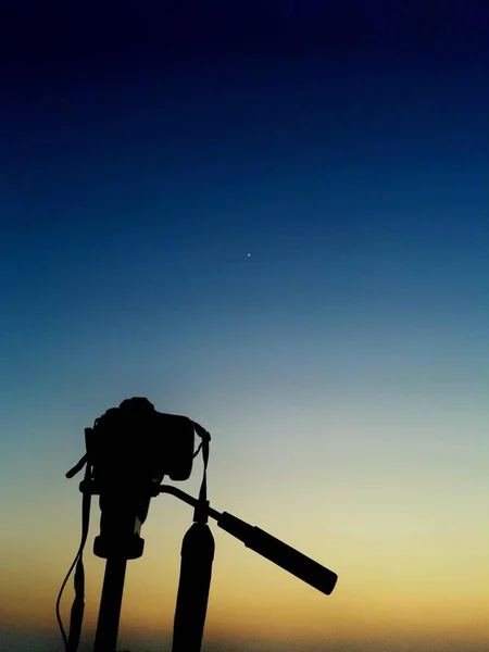 silhouette of golf player on tripod against blue sky