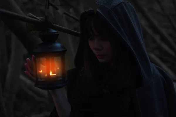 Girl holding lantern in dark forest