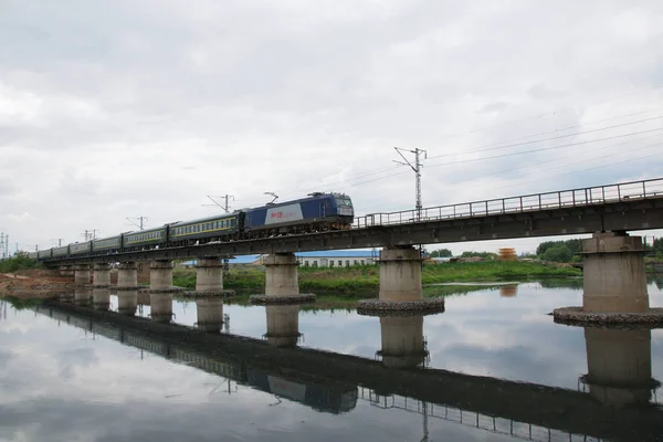 Train on bridge under cloudy sky