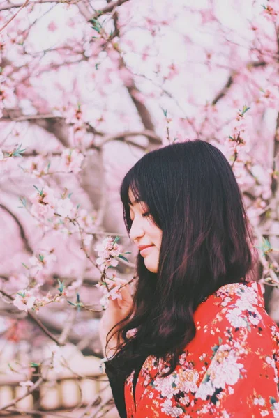 木の花でいっぱいの庭で陽気なアジアの女性 — ストック写真