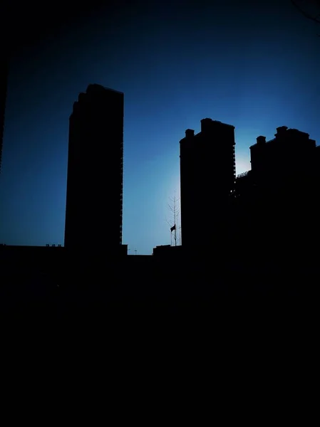 silhouette of a city with a big ben and a large sunset.