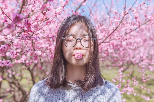 春の庭で花の近くでポーズをとる女性 — ストック写真