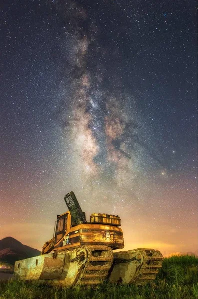 astronomy nebula night sky and old tank in field