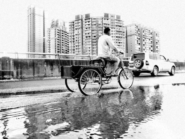man in black and white t-shirt riding on bicycle in city
