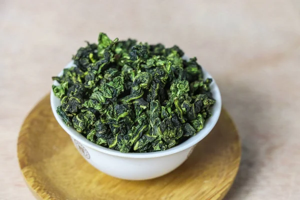 dried green tea leaves on a wooden background