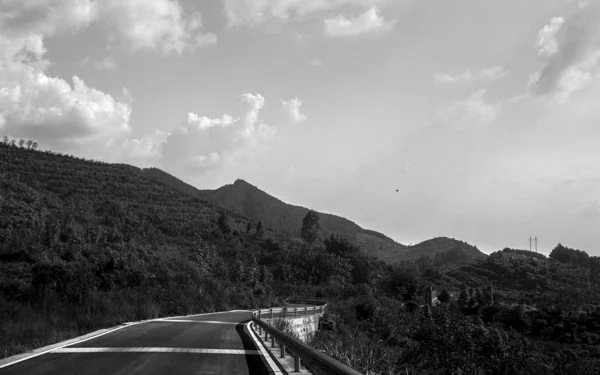 black and white image of a road in the mountains