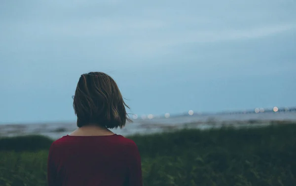 rear view of woman standing on the grass with a backpack