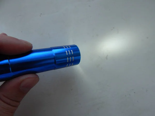 Hand flashlight shines in male hand — Stock Photo, Image