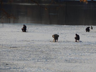 Balıkçılar buzda oturur ve nehirde balık yakalar.