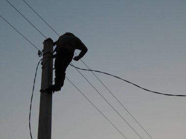 Elektrikçi direğin üzerinde özel kıyafetlerle çalışıyor