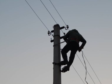Elektrikçi direğin üzerinde özel kıyafetlerle çalışıyor