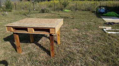 Çimlerin üzerinde ev yapımı palet masası var.