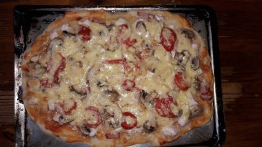 Hamur, peynir, mantar ve domatesli ev yapımı pizza.