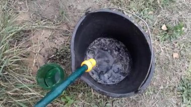 Su, hortumdan kovaya dökülür.