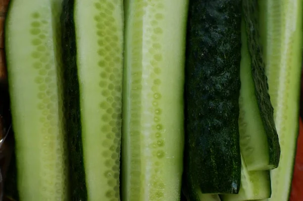 Komkommers in een rieten schaal op een snijplank gesneden komkommer voor het koken. — Stockfoto