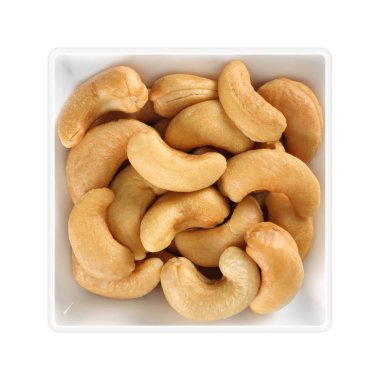 Beyaz arka plan üzerinde kare kase içinde kavrulmuş kaju fıstığı