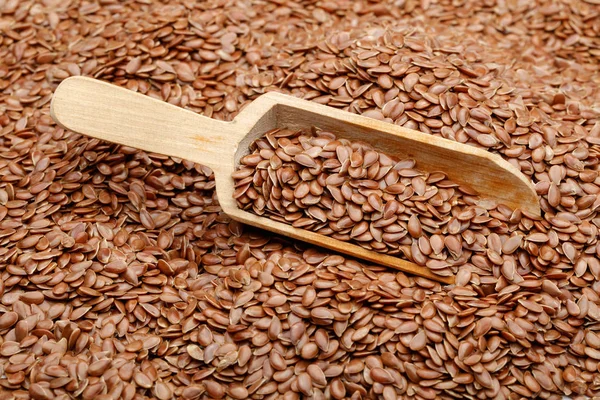Flax seeds in wooden scoop, full frame, macro shot