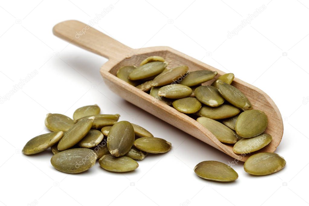 Peeled pumpkin seeds in wooden scoop isolated on white background