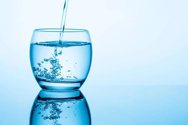 Fluyendo Agua Pura Vidrio Sobre Fondo Azul — Foto de Stock