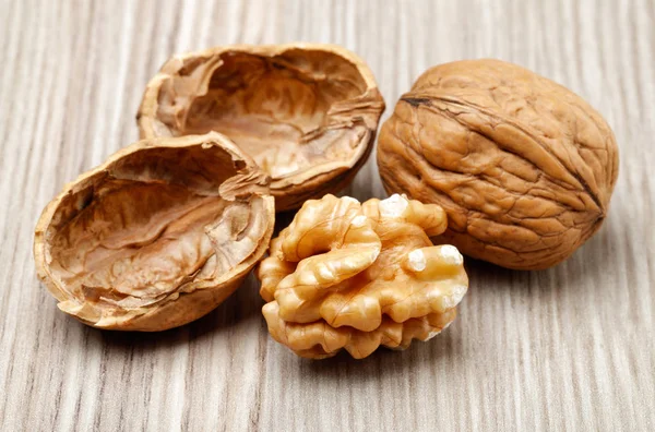 Whole and cracked walnuts on wooden board — Stock Photo, Image