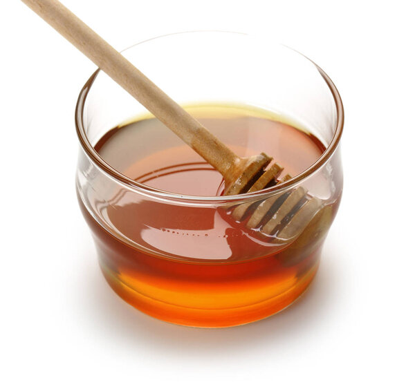 Honey with wooden dipper in glass bowl isolated
