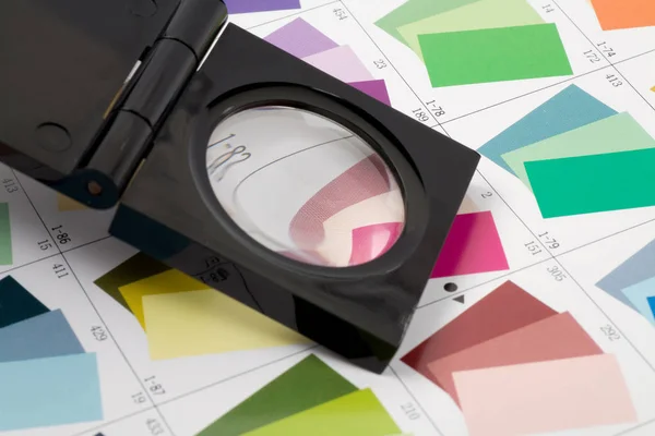 Glass loupe standing on colour swatch — Stock Photo, Image