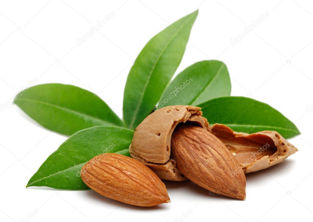 Almonds and green leaves isolated on white