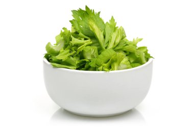 İzole edilmiş beyaz bir kasede doğranmış taze kereviz sapları.