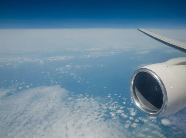 View of the aircraft engine that flies above the clouds. Airplane wing with engine in flight.