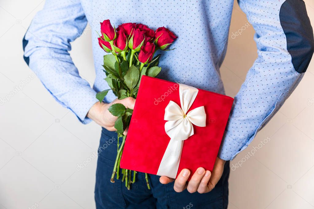 Romantic gift surprise, man hiding present,gift and holding red roses,couple love, romantic relationship,Valentines day,womans day, 8 march.