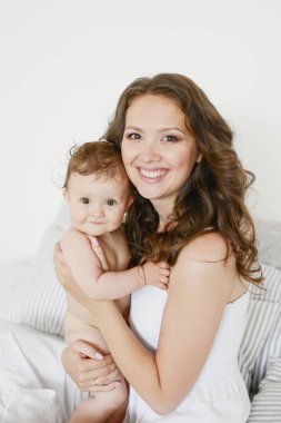 Anneler Günü 'nde küçük sevimli kızına sarılan mutlu bir anne. Kadınlar Günü. 8 Mart. Bahar selamları. Evde mutlu bir aile. Sağlıklı aile kavramı, anne ve kız bebek..