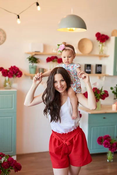 mom and daughter play in the kitchen, the kitchen is decorated with peonies