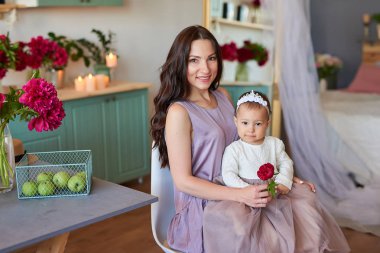 Anne ve kızı mutfakta zarif elbiseler peonies ile dekore edilmiş