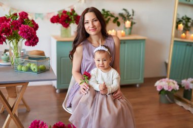 Anne ve kızı mutfakta zarif elbiseler peonies ile dekore edilmiş