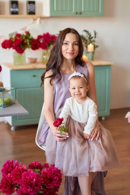 Anne ve kızı mutfakta zarif elbiseler peonies ile dekore edilmiş