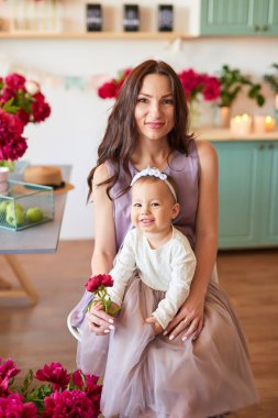 Anne ve kızı mutfakta zarif elbiseler peonies ile dekore edilmiş